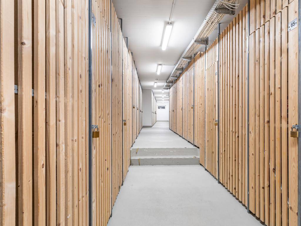 Langer Kellergang mit zahlreichen abschließbaren Holzabteilen für zusätzlichen Stauraum.