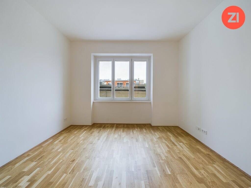 Leeres Schlafzimmer mit Parkettboden und Blick auf die Stadt, bietet viel Gestaltungspotenzial.