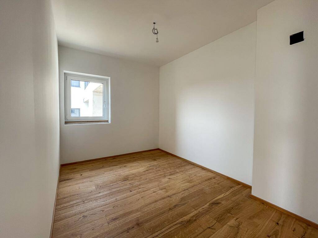 Kleineres Schlafzimmer mit Holzboden und Fenster, ideal als Kinder- oder Gästezimmer.