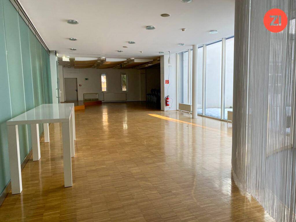 Großer, heller Raum mit Holzboden und hohen Fenstern, ideal für Veranstaltungen oder Büros.