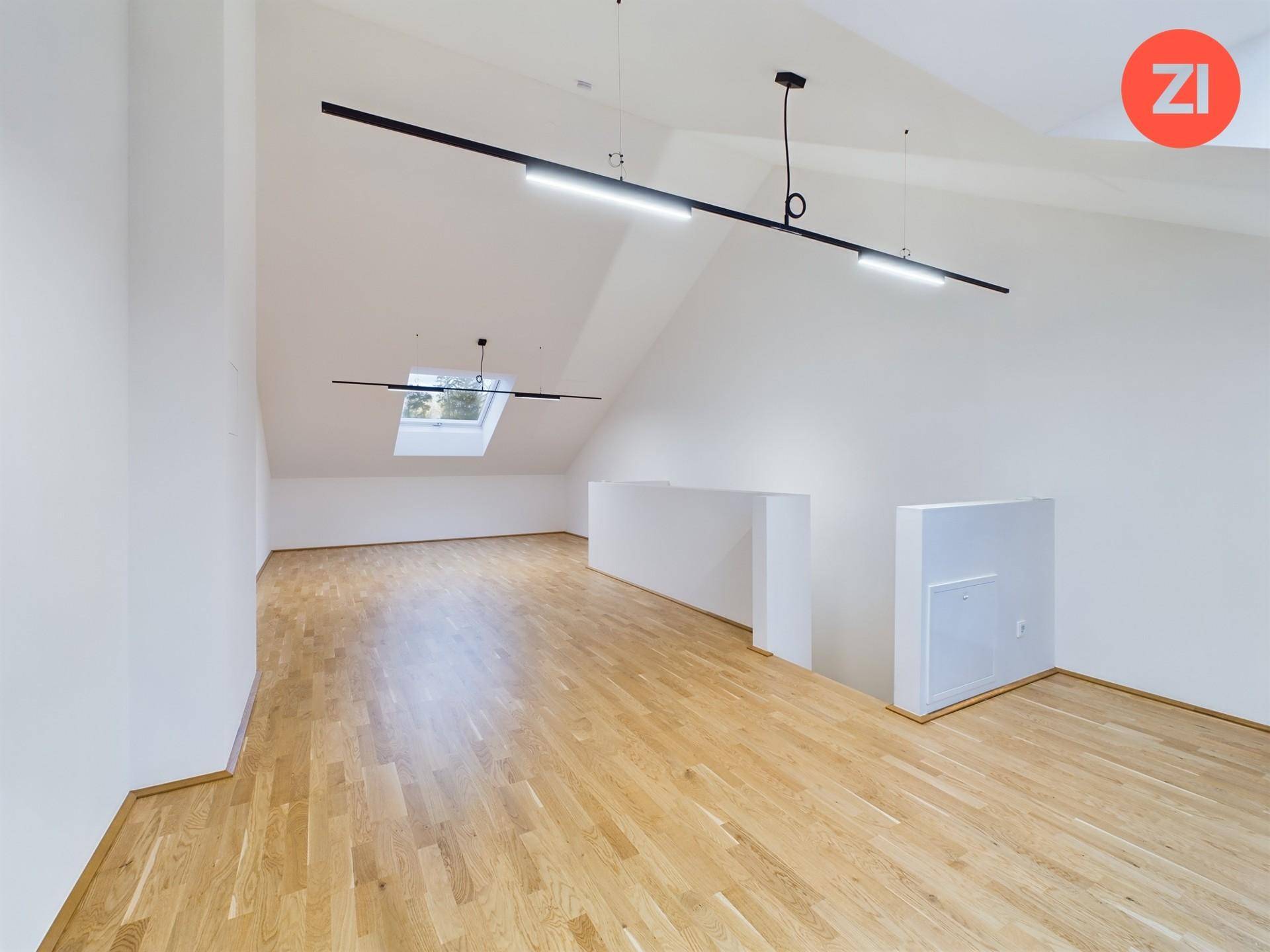 Geräumiger Dachboden mit Holzboden, schrägen Wänden und Dachfenster für natürliches Licht.