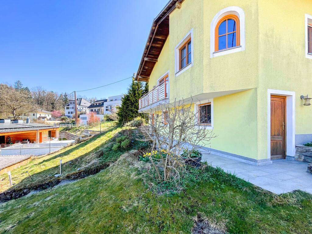 Seitenansicht des gelben Hauses mit kleinem Balkon und Zugang zum Gartenbereich.