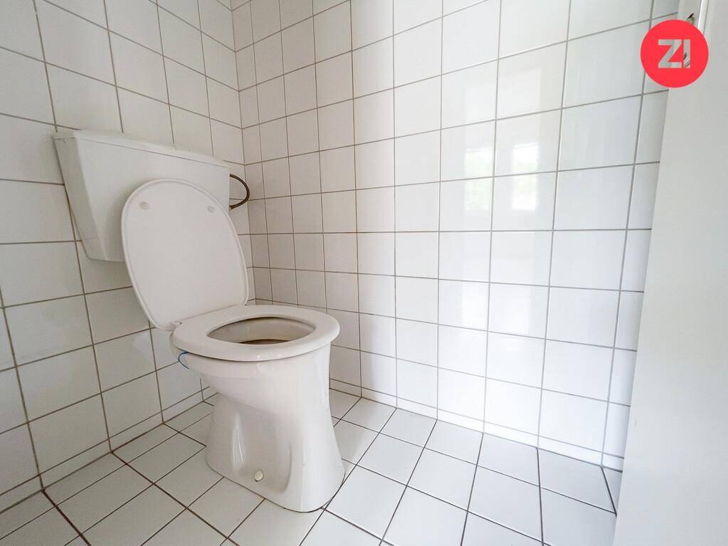 Separates WC mit weißen Fliesen und einer Standardtoilette.