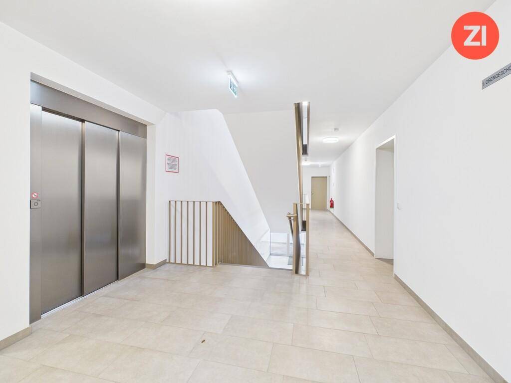 Moderner Hausflur mit Aufzug und Treppenhaus, hell und sauber gehalten.