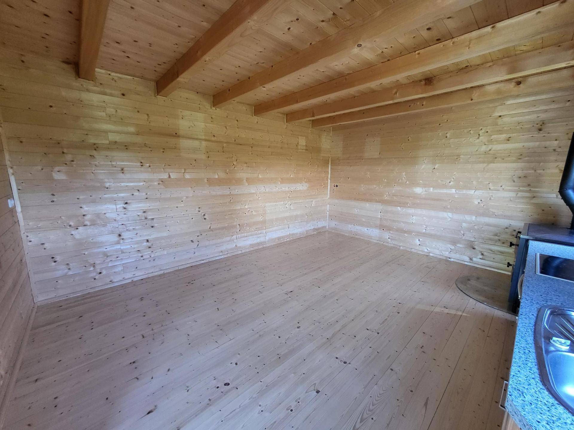 Heller Wohnbereich mit durchgehenden Holzwänden und -boden, bietet eine warme und natürliche Atmosphäre.
