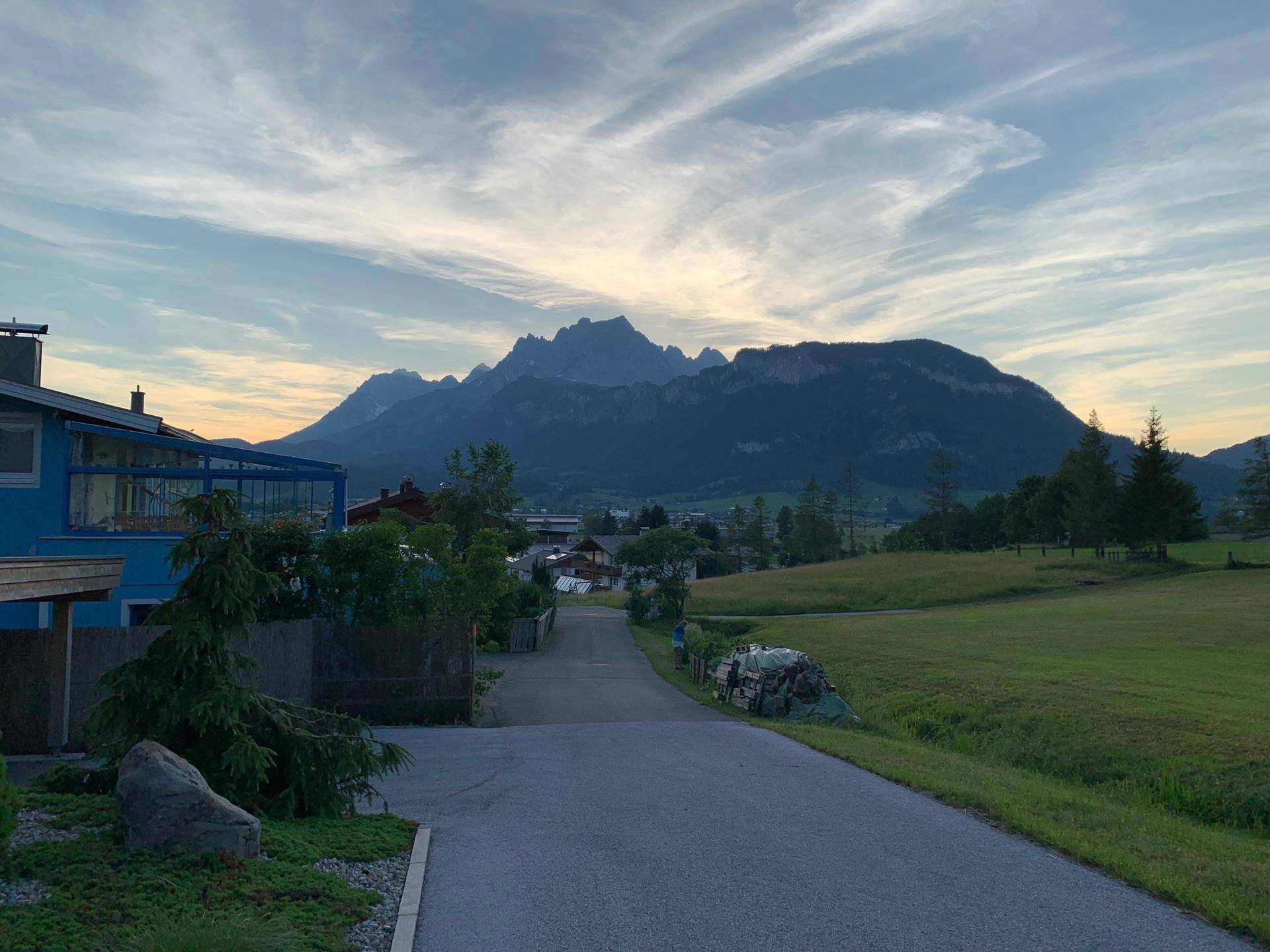 Malerischer Blick auf die umliegende Berglandschaft und grüne Felder bei Sonnenuntergang.