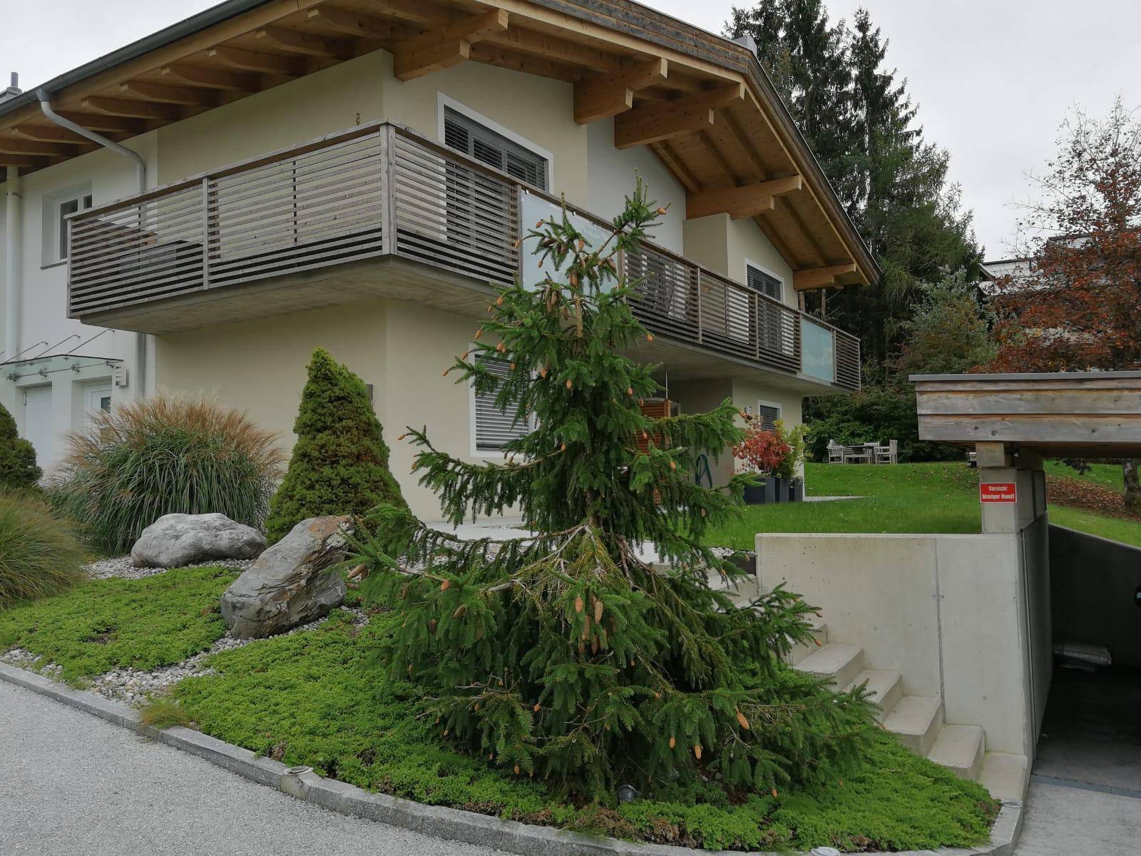 Modernes Haus mit Balkonen, gepflegtem Vorgarten und Zufahrt zur Tiefgarage.