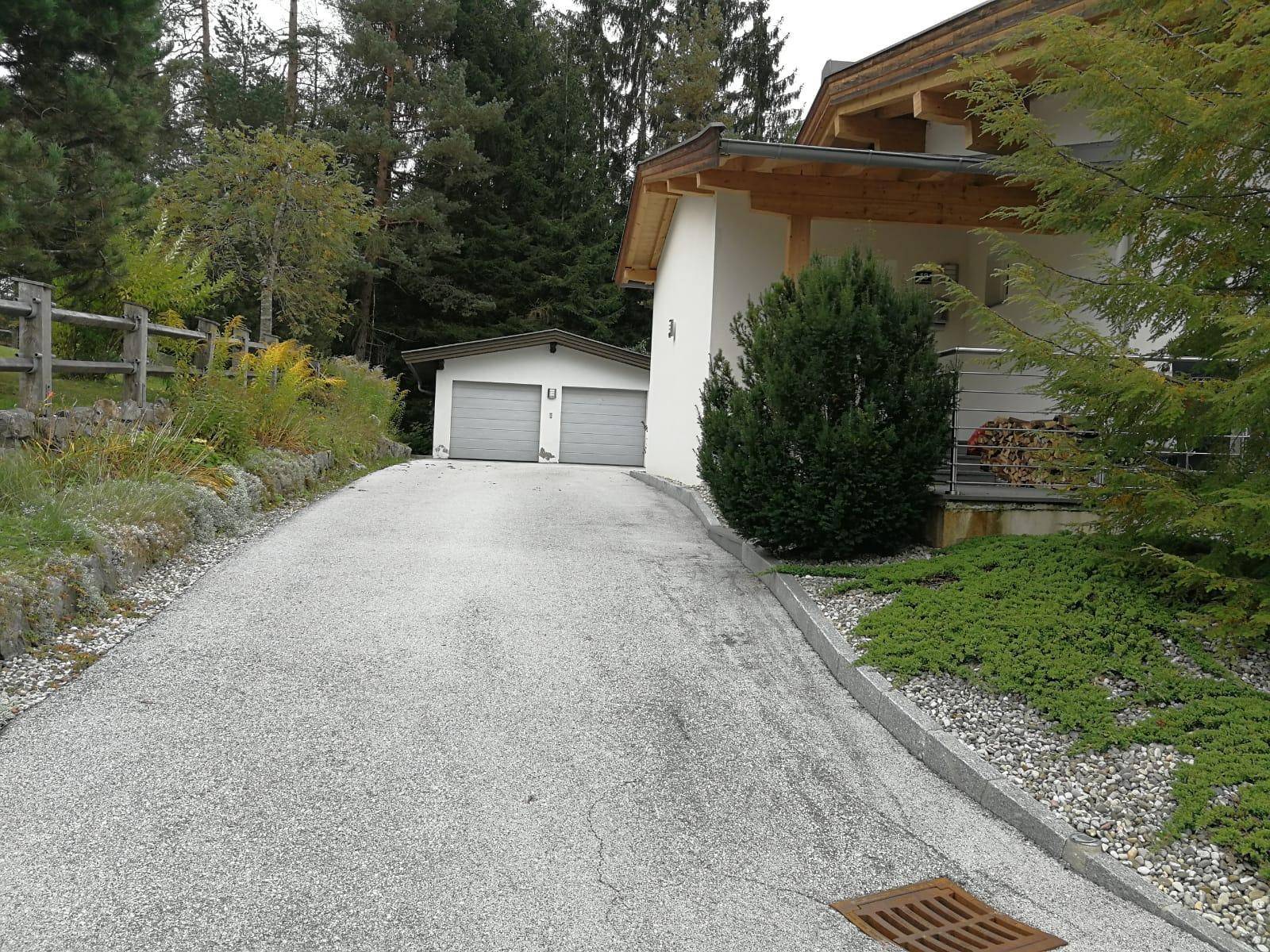 Zufahrt zum Haus mit Doppelgarage und umgebender Natur.