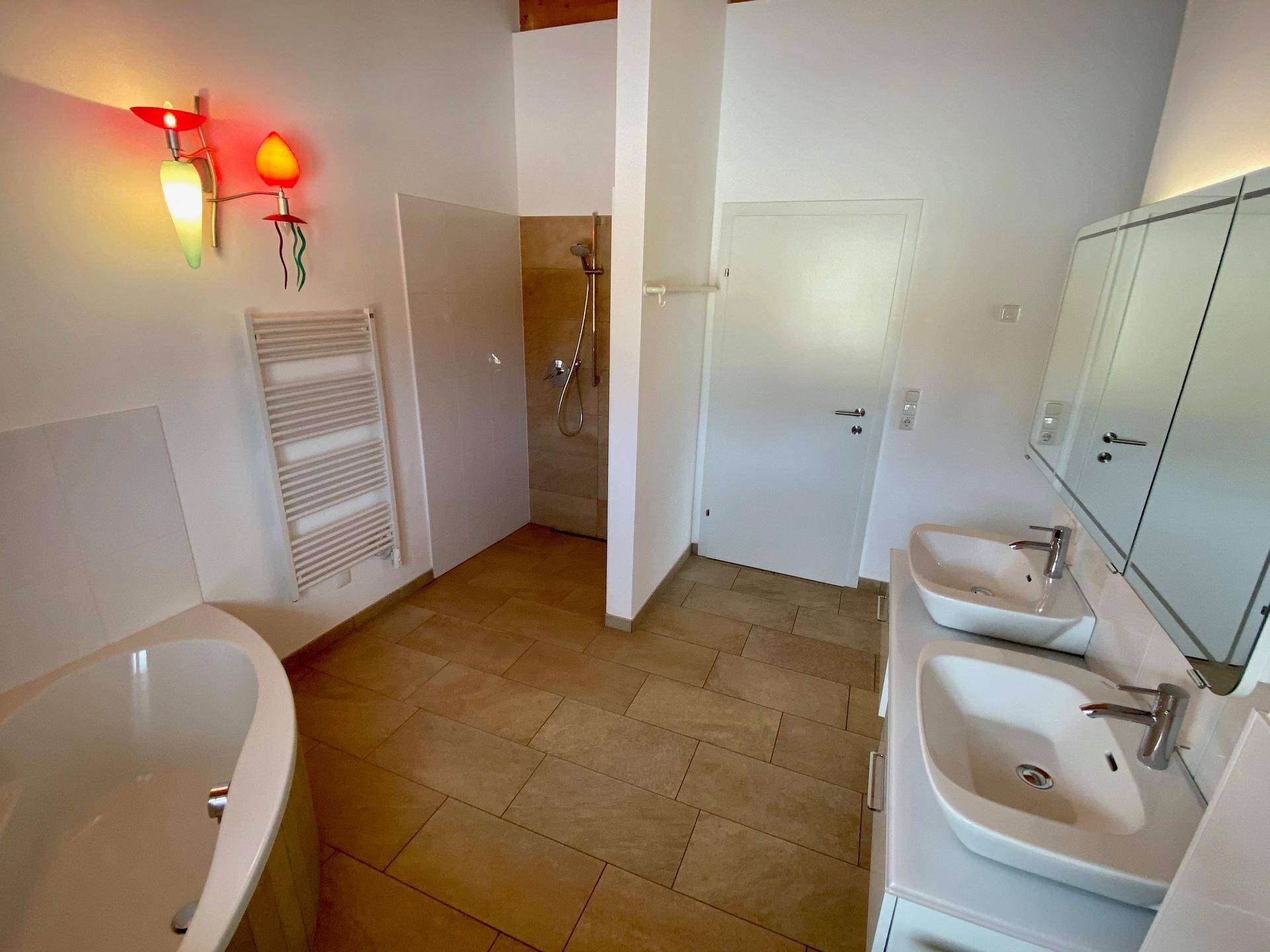 Modernes Badezimmer mit Badewanne, Doppelwaschbecken, Dusche und Handtuchheizkörper.