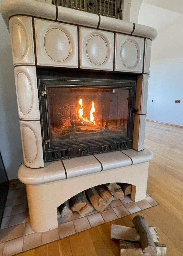 Nahaufnahme eines brennenden Kachelofens mit Holzscheiten, der eine gemütliche Atmosphäre schafft.