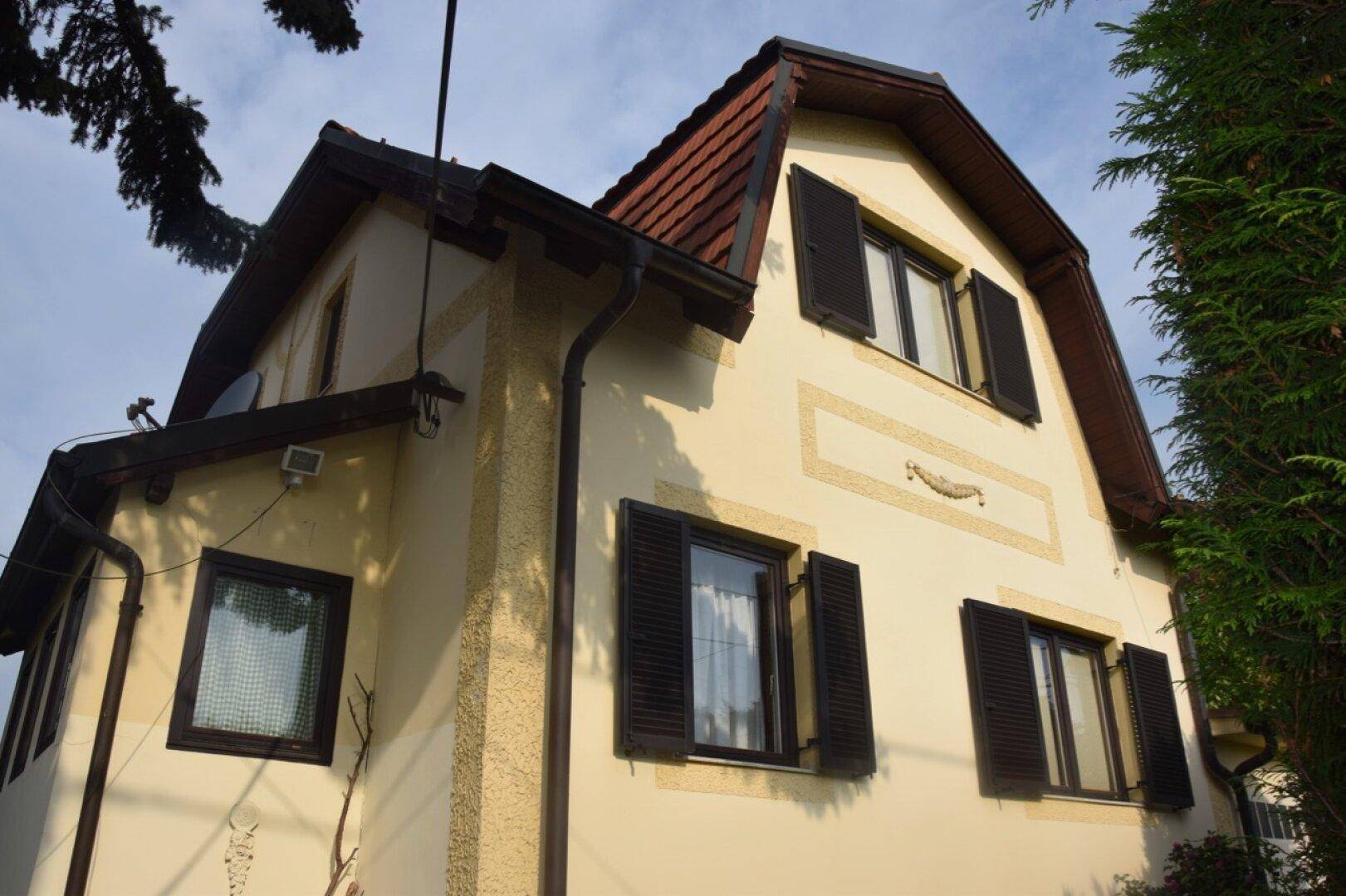 Fassade eines Hauses mit traditionellen Fensterläden und einem markanten Mansarddach.