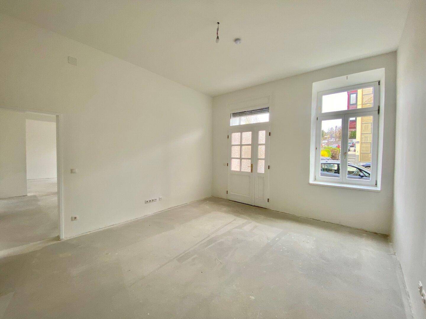 Unmöblierter Raum mit Fenster und Tür, bietet viel Potenzial für individuelle Nutzung und Gestaltung.