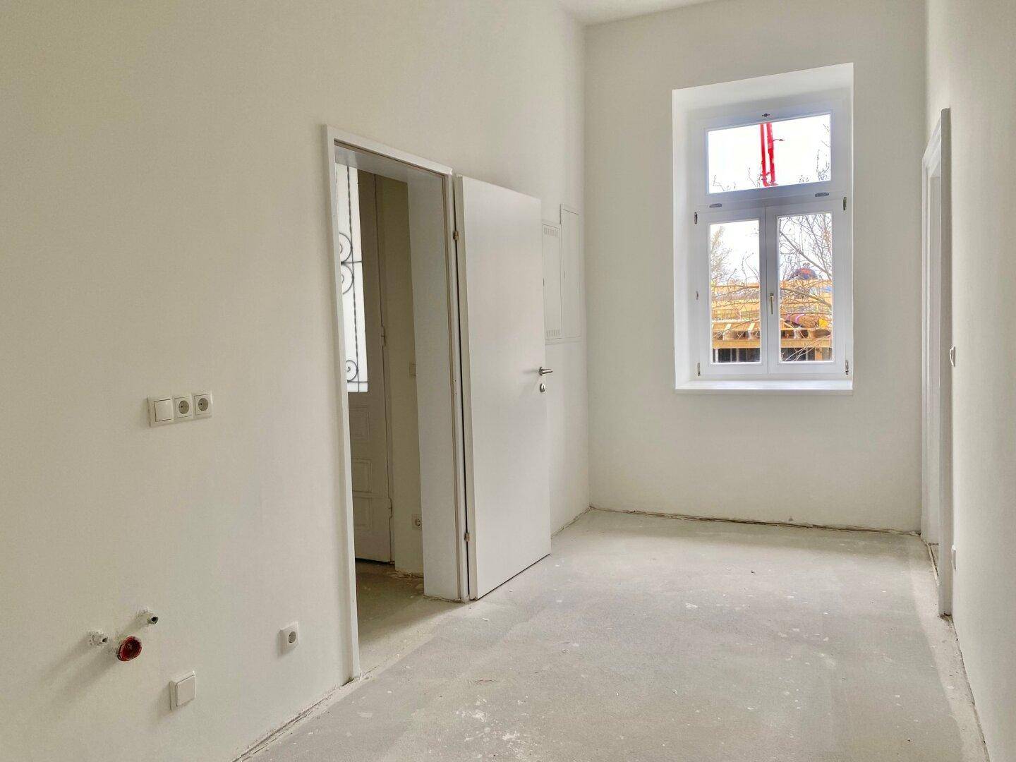 Unmöblierter Raum mit einem Fenster und einer Tür, bietet Potenzial für verschiedene Nutzungsmöglichkeiten.