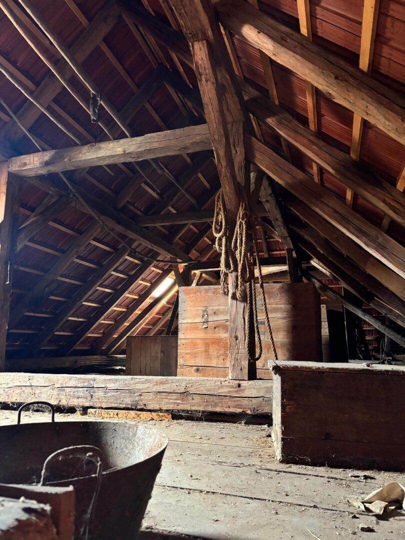 Geräumiger Dachboden mit sichtbaren Holzbalken und Ziegeln, der viel Stauraum bietet.