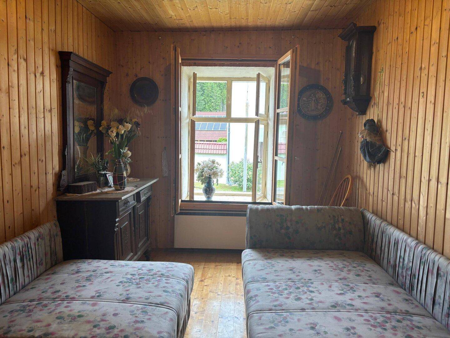 Rustikales Zimmer mit Holzvertäfelung, zwei Einzelbetten und Blick in den Garten.