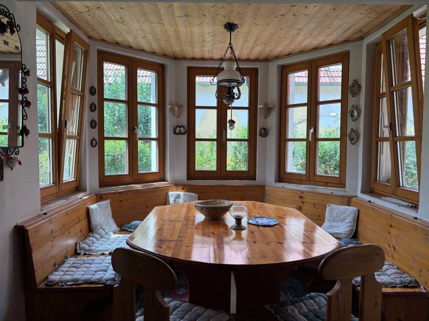Gemütlicher Essbereich mit Holztisch, Eckbank und vielen Fenstern für natürliches Licht.