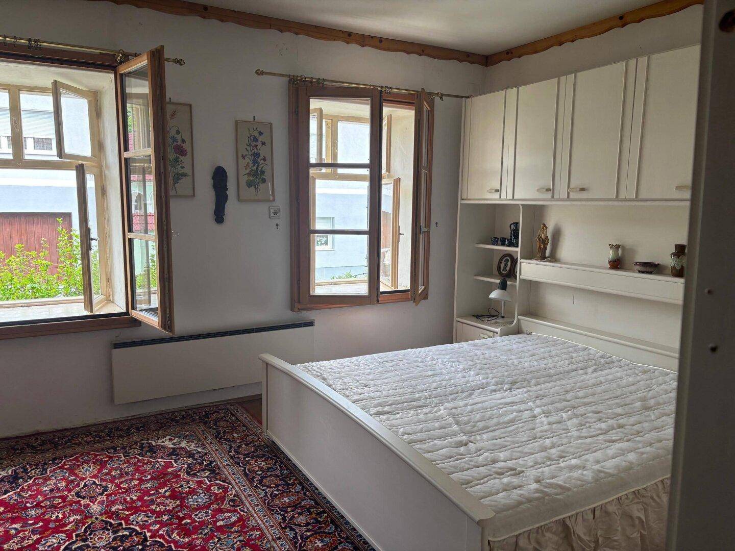 Helles Schlafzimmer mit Doppelbett, Einbauschränken und Blick ins Grüne.