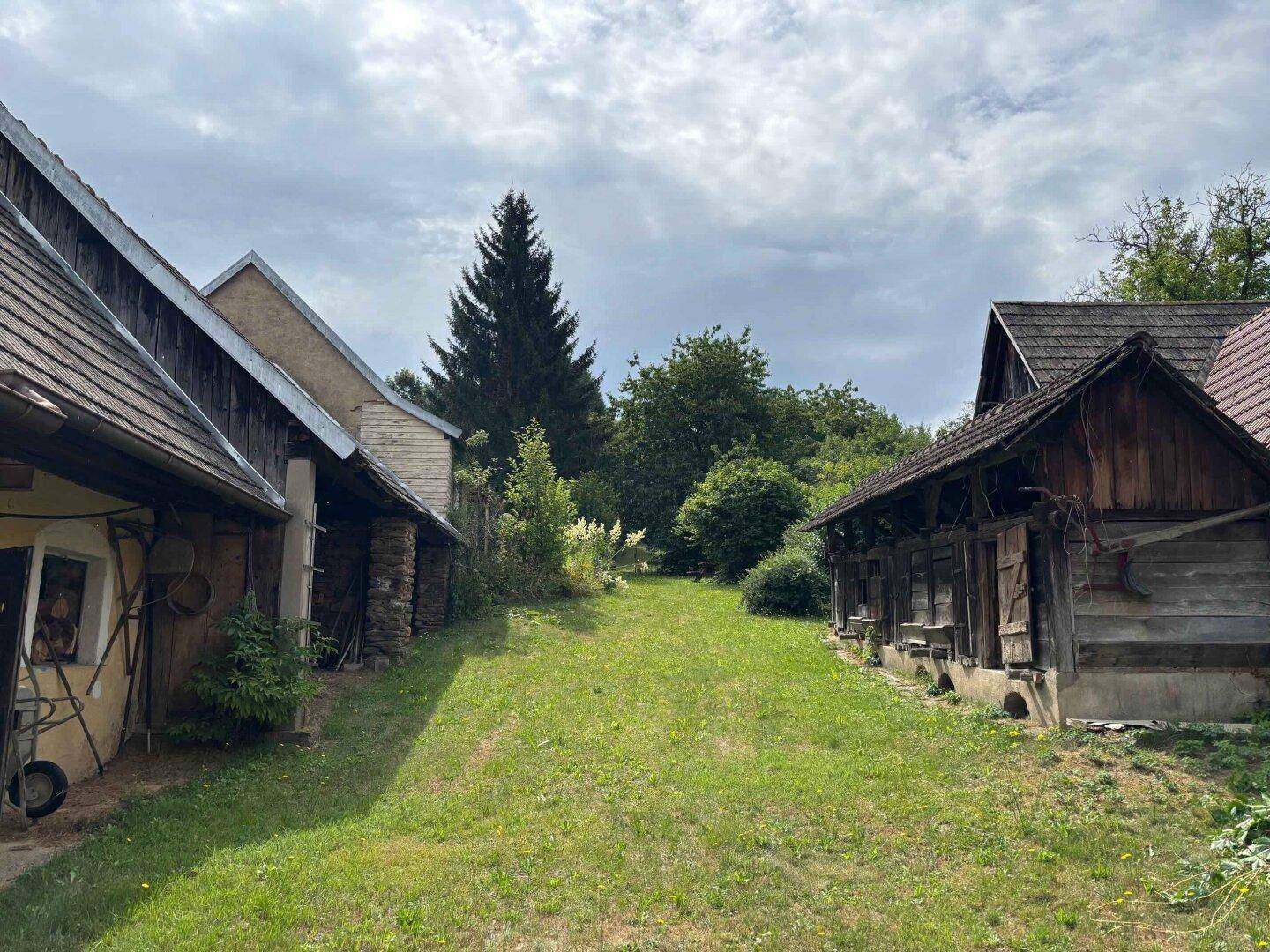Ländliches Anwesen mit mehreren traditionellen Gebäuden und einer großen Rasenfläche.