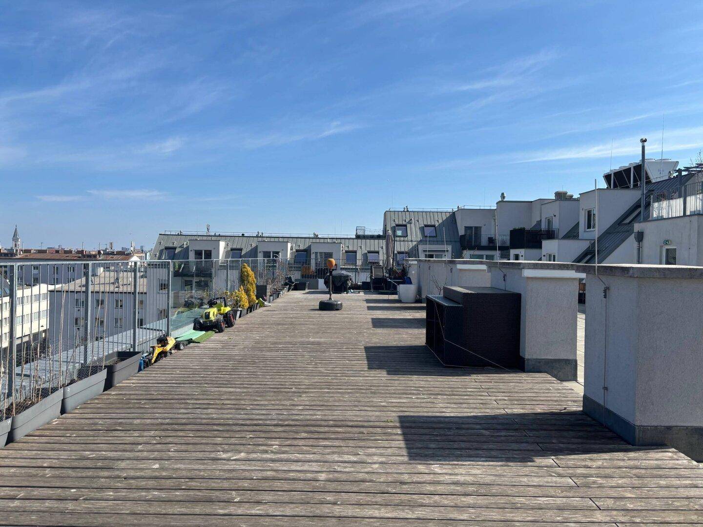 Weitläufige Dachterrasse mit Holzboden und einem beeindruckenden Panoramablick über die Stadtlandschaft.