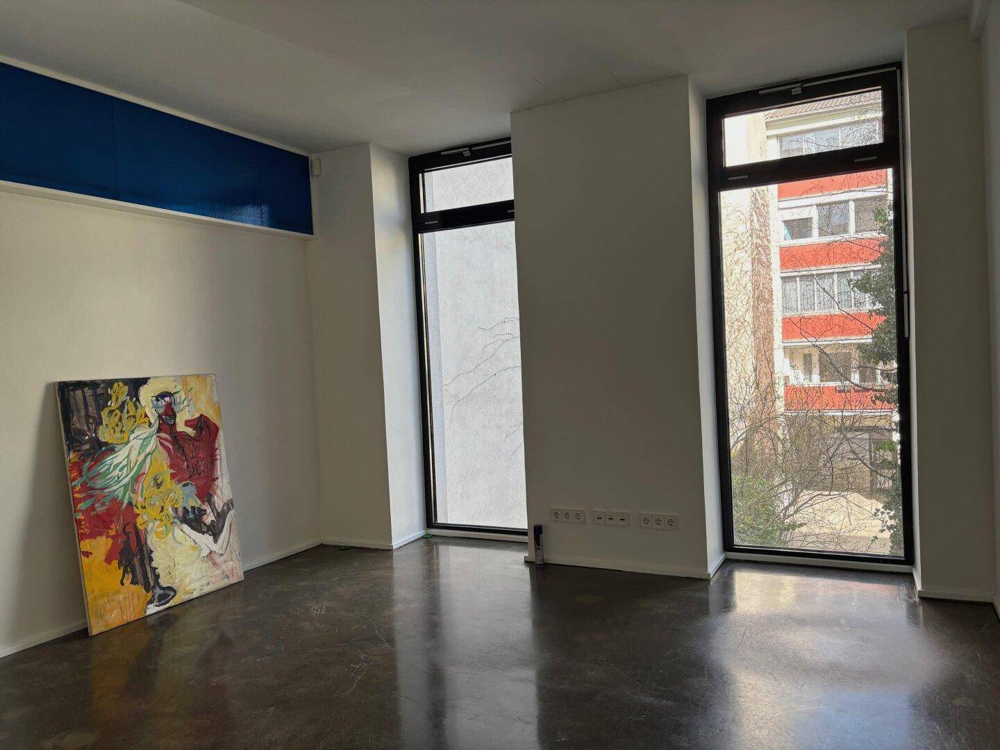 Moderner Raum mit großen Fenstern, von denen eines mattiert ist, und Blick auf die umliegenden Gebäude.