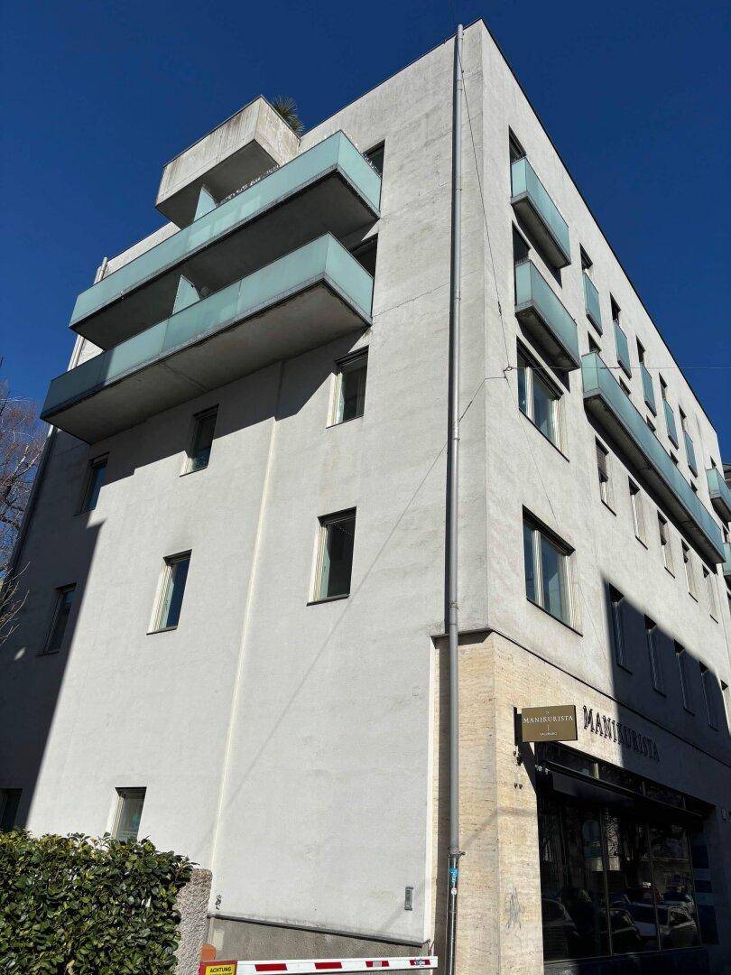 Mehrstöckiges Gebäude mit moderner Architektur, Balkonen und einer Geschäftseinheit im Erdgeschoss.