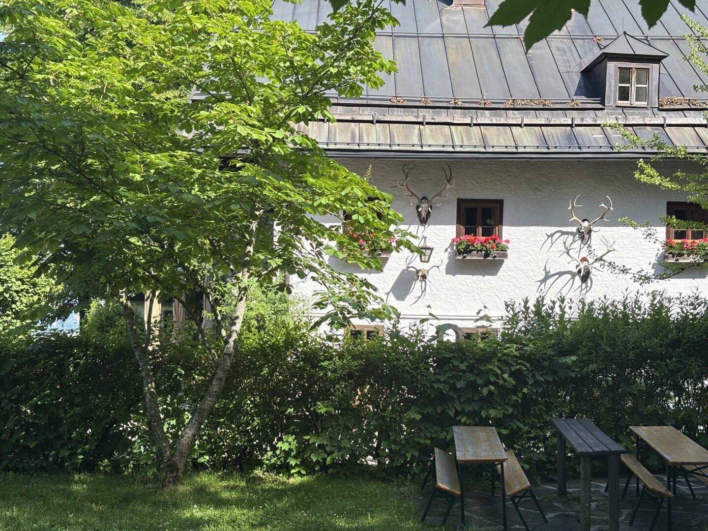 Traditionelles Haus mit Hirschgeweihen an der Fassade und einem grünen Gartenbereich.