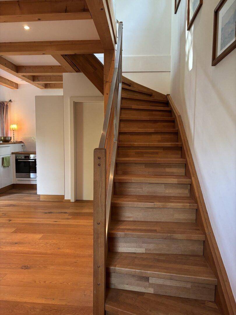 Elegante Holztreppe mit modernem Geländer, die die Etagen des Hauses verbindet.