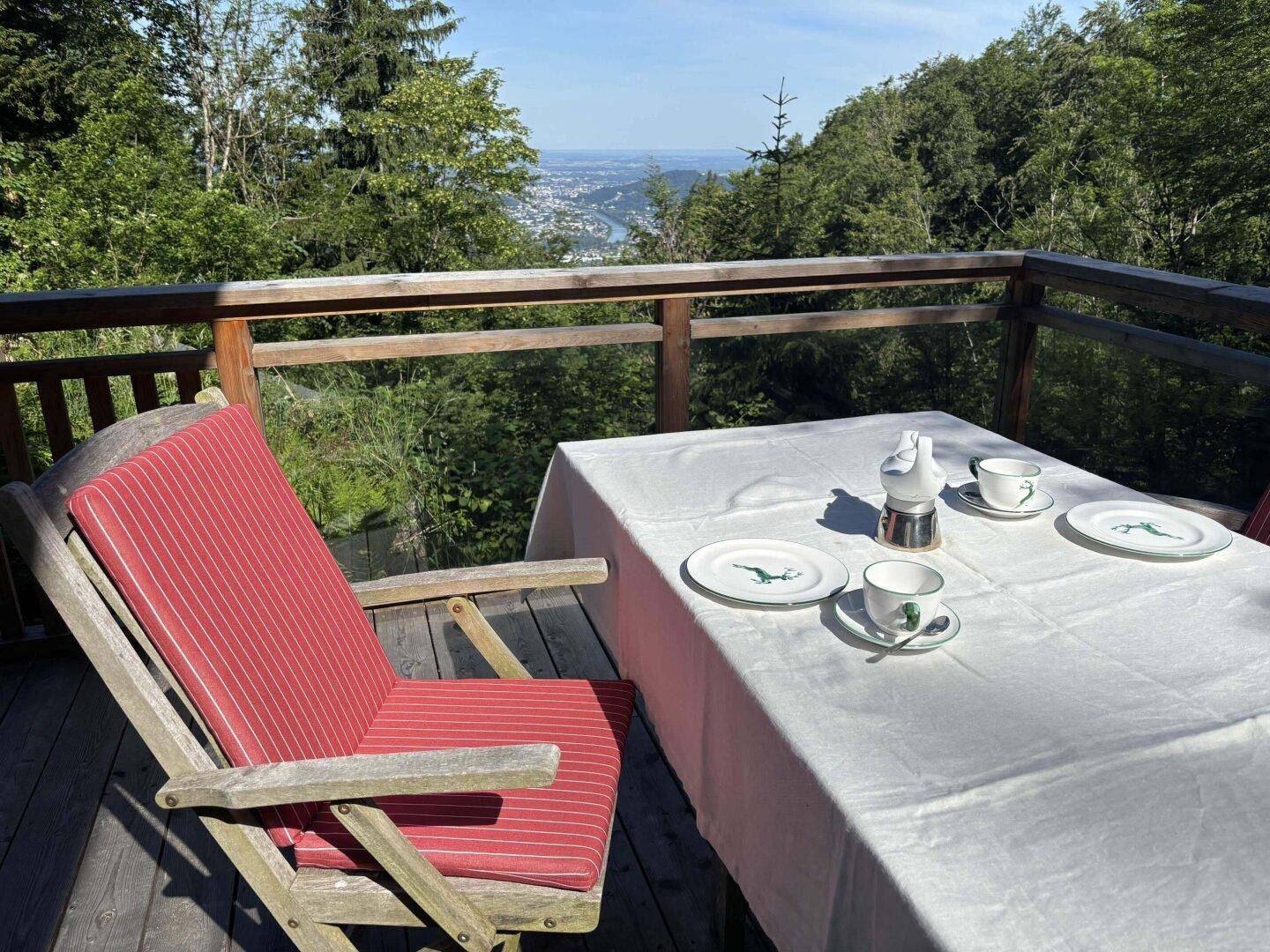 Sonniger Essbereich auf der Terrasse mit Holztisch und weitem Blick über das Tal.