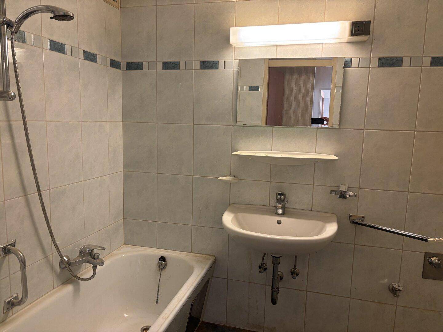 Badezimmer mit Badewanne, Waschbecken und Wandfliesen in hellem Design.