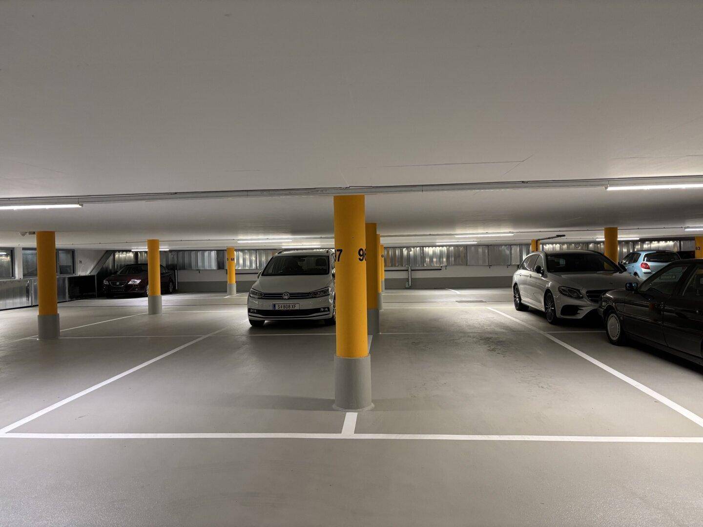 Tiefgarage mit mehreren Stellplätzen und gelben Säulen.