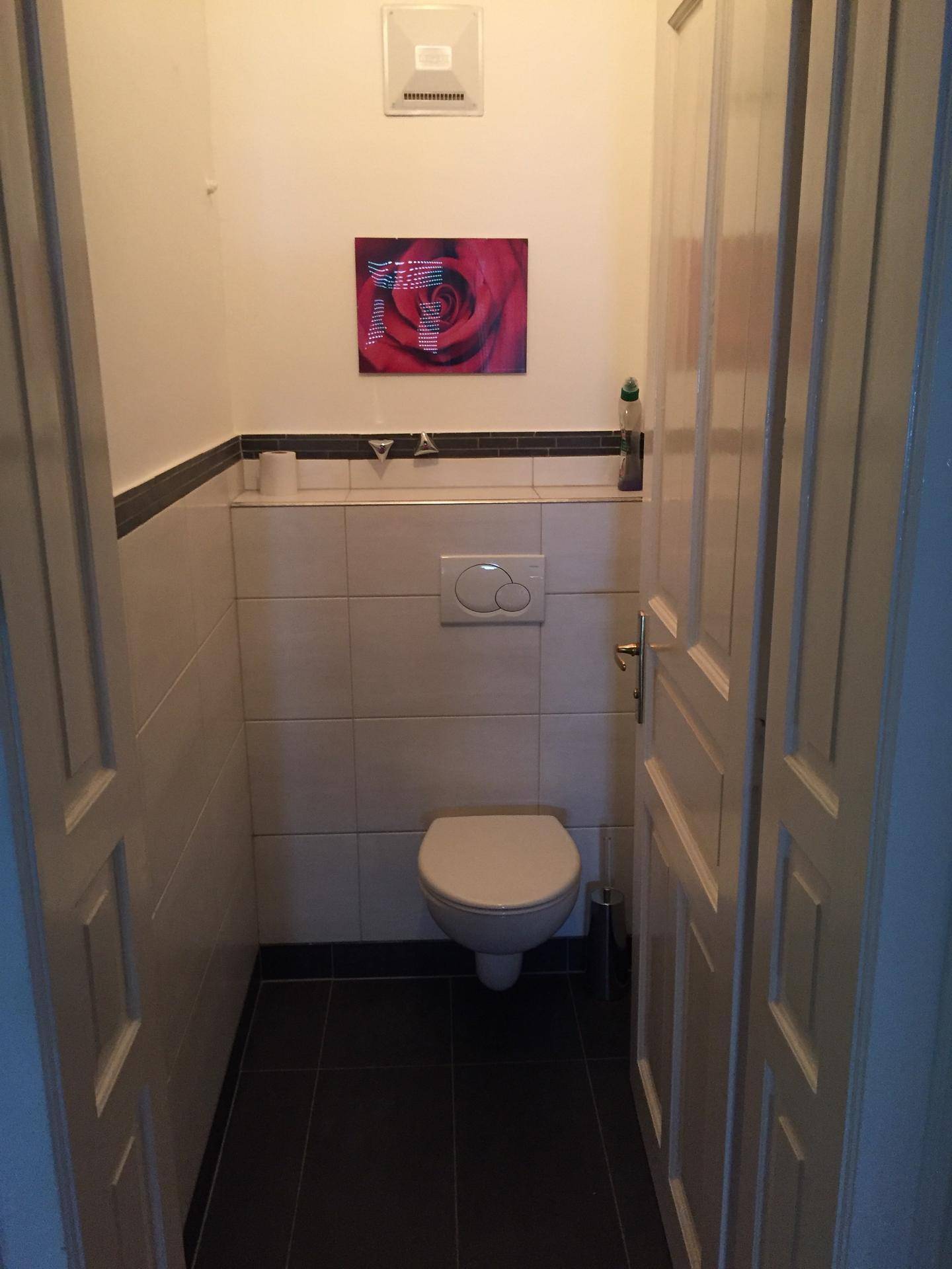 Kleines Gäste-WC mit Wand-WC, Fliesen und einem roten Wandbild.