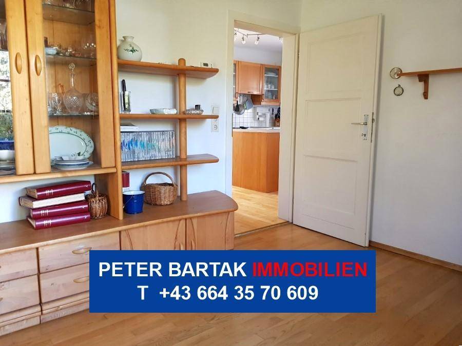 Heller Flur mit weißer Tür und Blick in die angrenzende Küche.