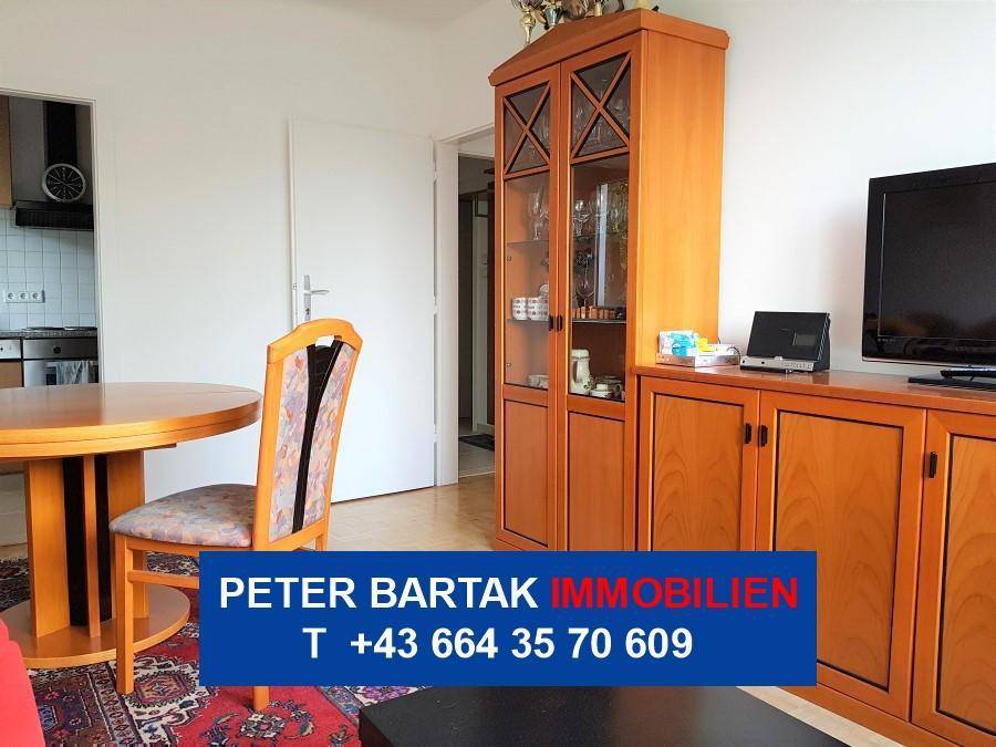 Wohn-Essbereich mit Holztisch, Schrank und offenem Zugang zu einem weiteren Raum.