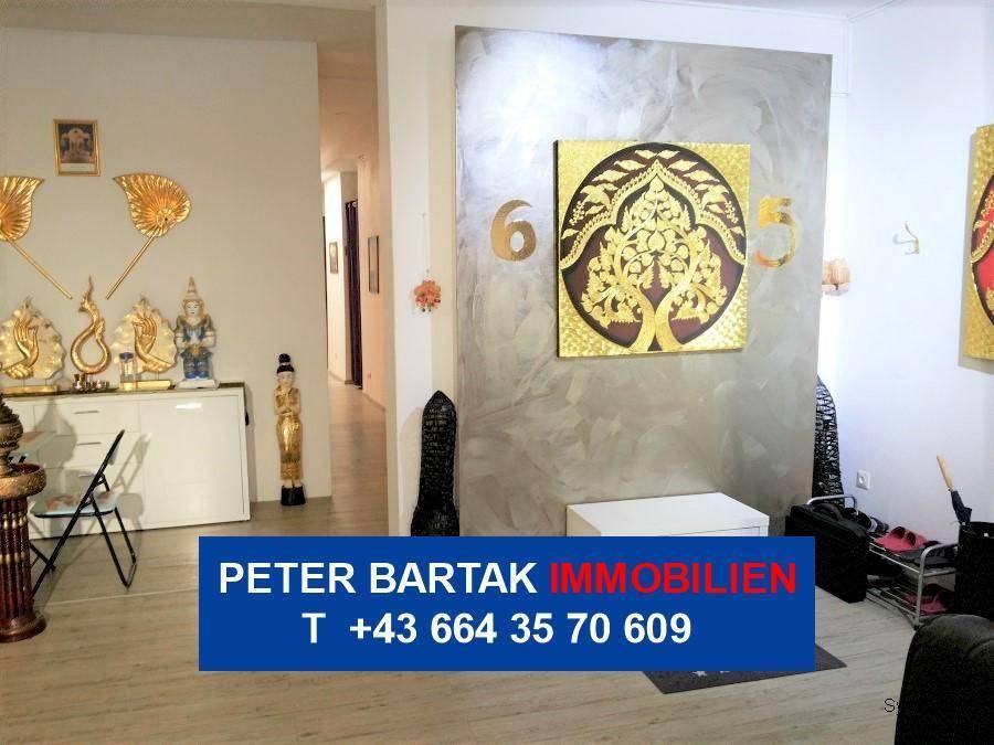 Innenraum mit goldener Wanddekoration, einer grauen Akzentwand und einem Durchgang zu einem weiteren Bereich.
