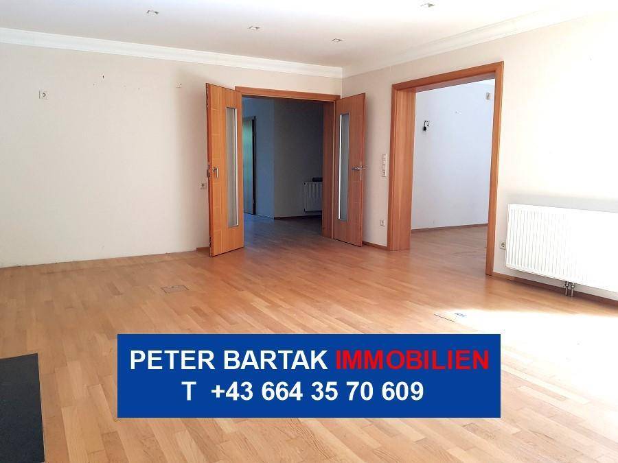 Heller Raum mit Parkettboden und zwei offenen Holztüren, die zu weiteren Zimmern führen.