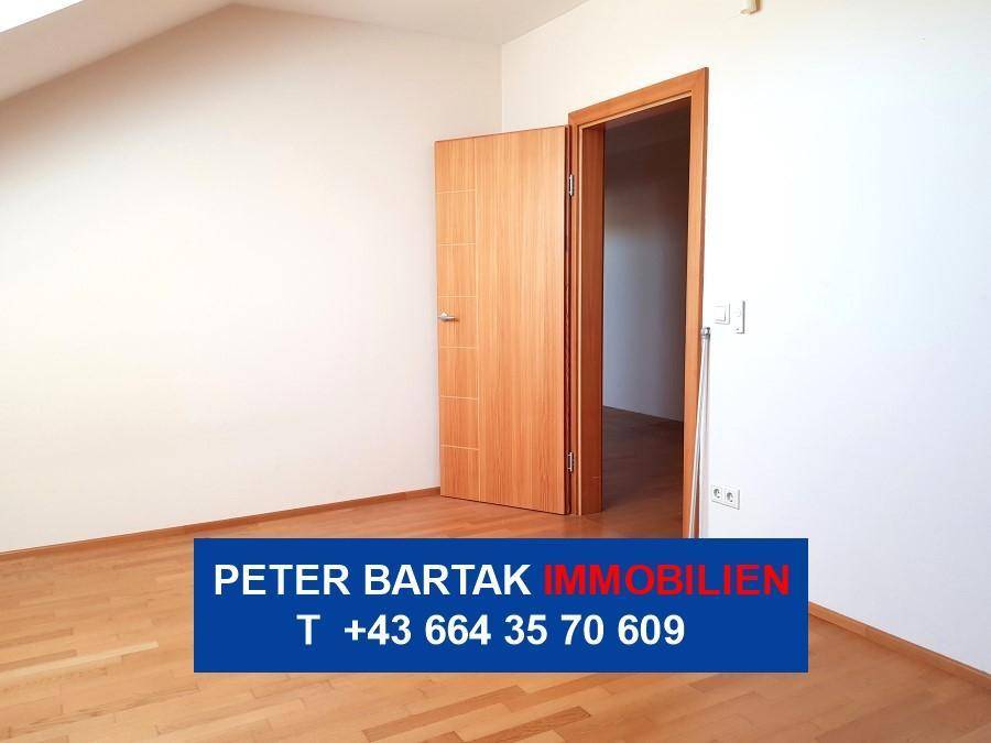 Dachzimmer mit Parkettboden, schräger Decke und offener Holztür, bietet vielseitige Nutzung.