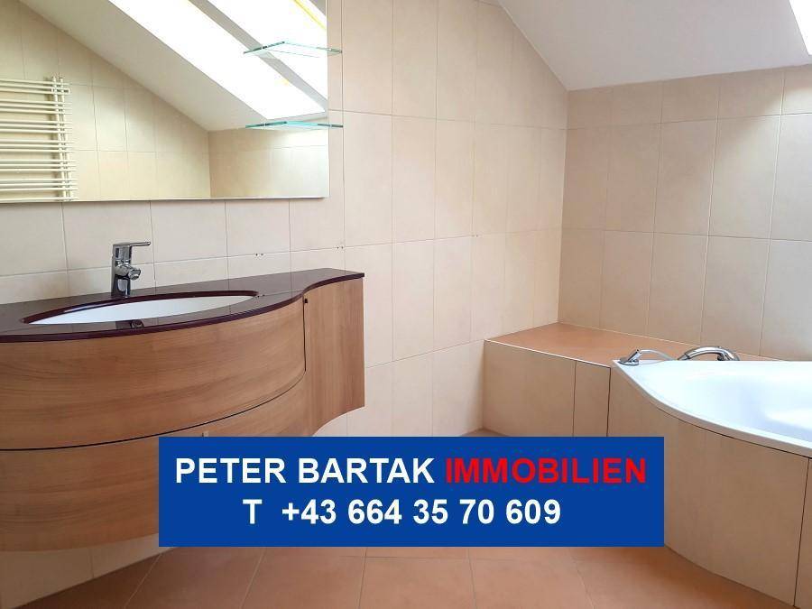 Modernes Badezimmer im Dachgeschoss mit Fliesen, geschwungenem Waschtisch, Badewanne und Dachfenster.