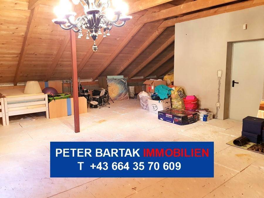 Unfertiger Dachboden mit sichtbaren Holzbalken und Kronleuchter, bietet viel Stauraum.