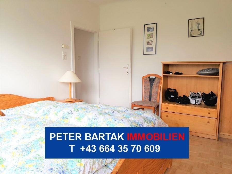 Schlafzimmer mit Holzbett, Nachttischlampe und einem praktischen Schrank für Kleidung.