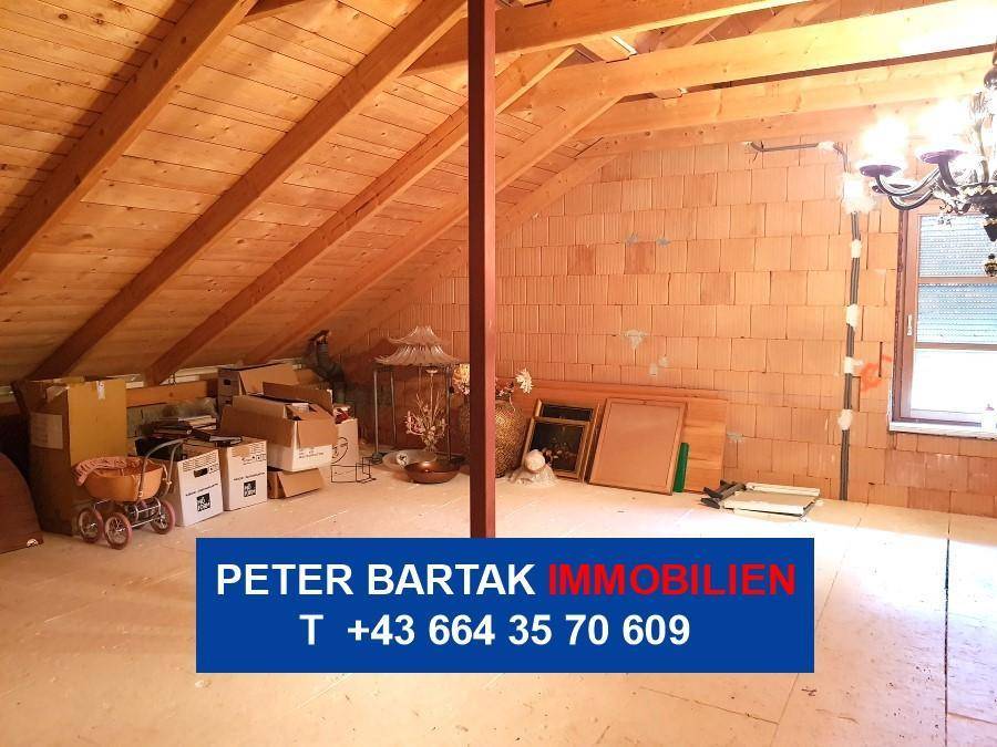 Geräumiger Dachboden mit unverputzten Ziegelwänden und Holzbalken, ideal für Ausbau.