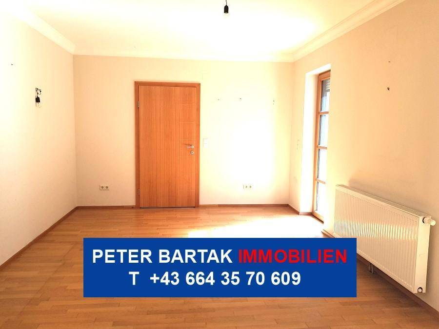 Geräumiger Raum mit Parkettboden, Fenster, Heizkörper und einer Holztür, ideal für verschiedene Nutzungen.