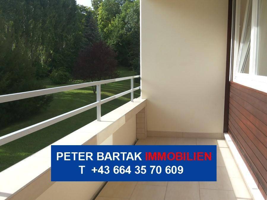 Heller Balkon mit weißem Geländer und Blick ins Grüne, ideal für entspannte Stunden im Freien.
