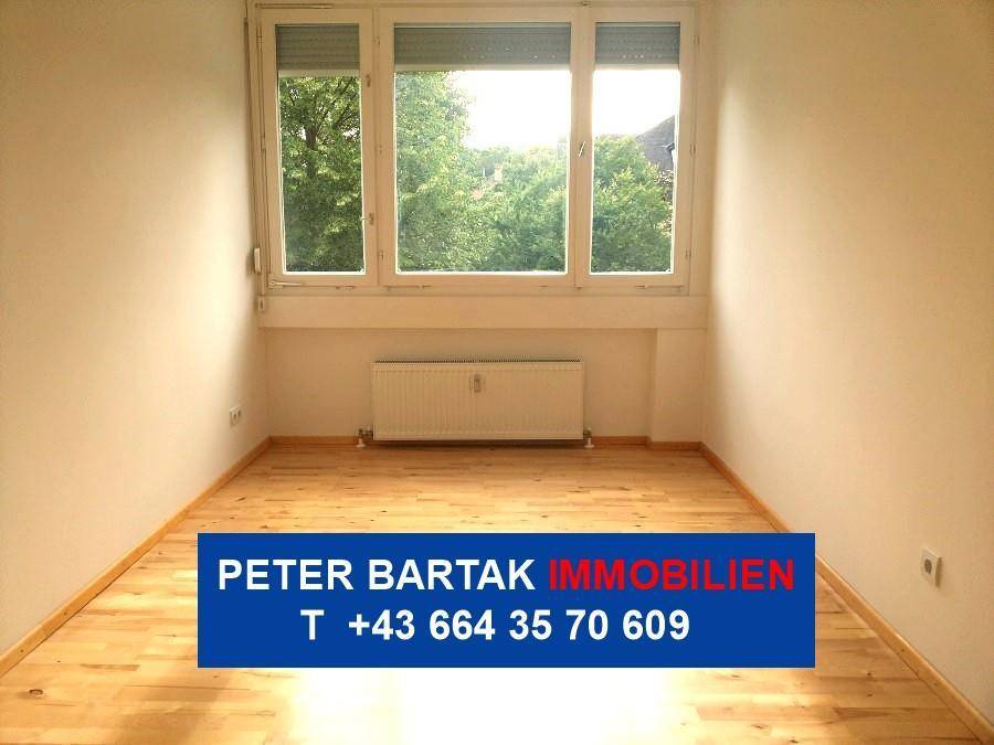 Geräumiges Zimmer mit hellem Parkettboden und großen Fenstern, die eine angenehme Atmosphäre schaffen.