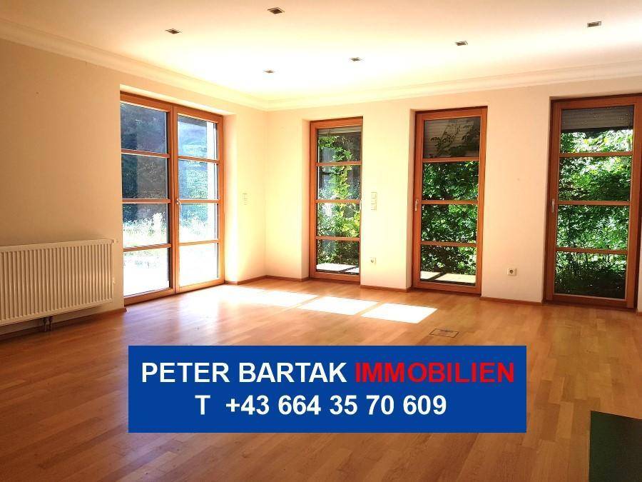Helles Wohnzimmer mit Parkettboden, vielen Fenstern und Zugang zum Außenbereich.