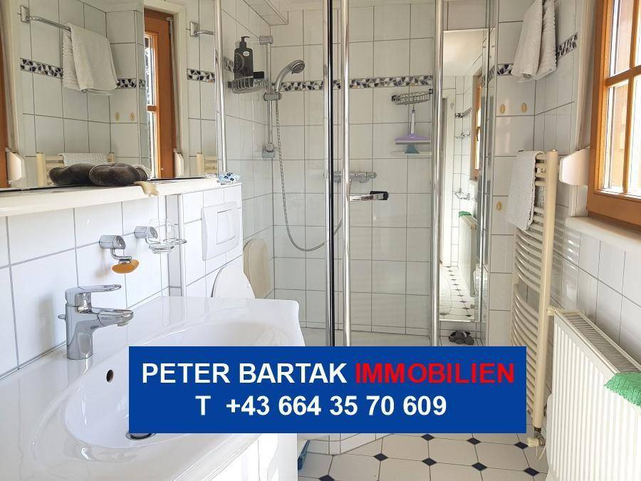 Modernes Badezimmer mit Duschkabine, Waschbecken und beheiztem Handtuchhalter.
