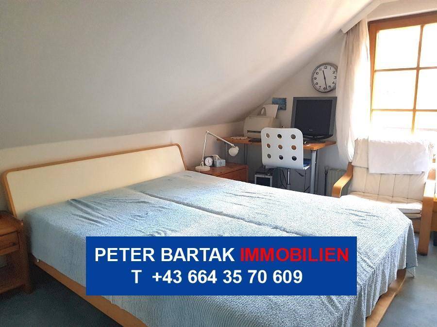 Gemütliches Schlafzimmer mit Doppelbett, Schreibtisch und Dachschräge.