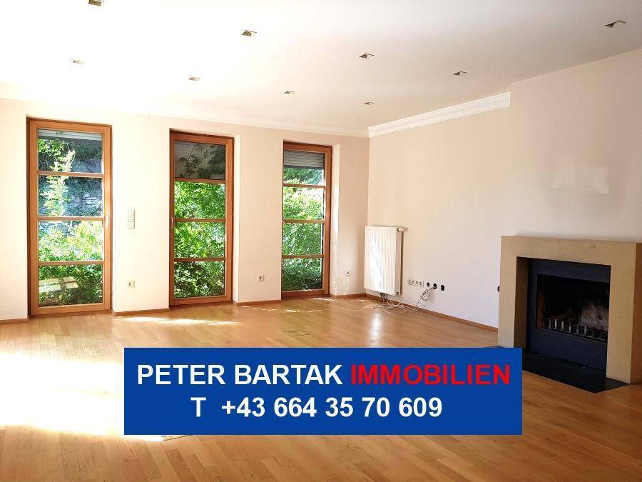 Geräumiges Wohnzimmer mit Parkettboden, Kamin und großen Fenstern mit Blick ins Grüne.