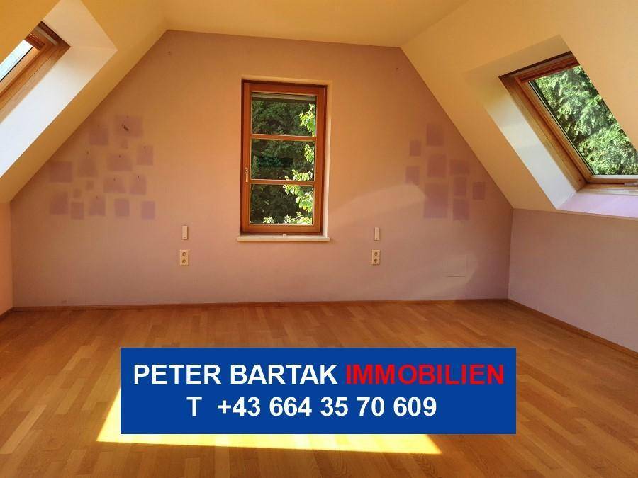 Dachzimmer mit Parkettboden, schräger Decke, Fenster und Dachfenster, bietet viel Tageslicht.