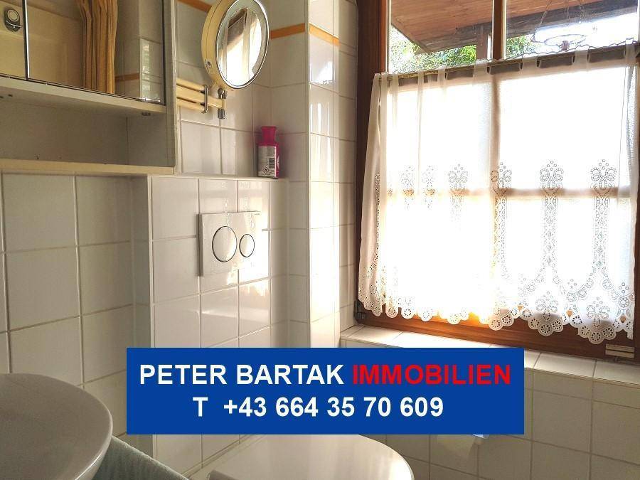 Badezimmer mit Toilette, Spiegel und Fenster für Tageslicht.
