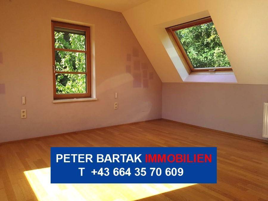 Heller Dachraum mit Holzfußboden und Dachfenster, ideal als Schlafzimmer nutzbar.